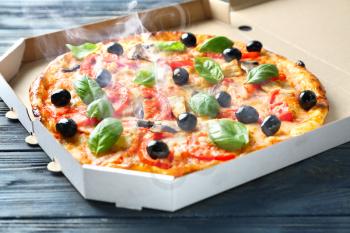 Box with tasty hot pizza on wooden table�