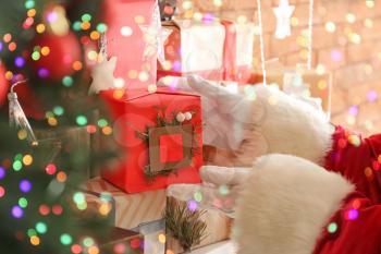 Santa Claus putting gift box on mantelpiece, closeup�