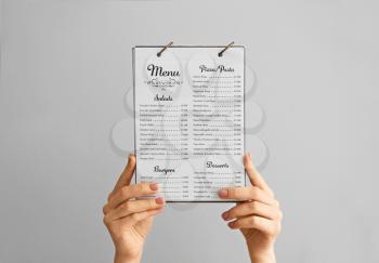 Female hands with menu on grey background�