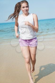 Attractive young woman running alone on the beach