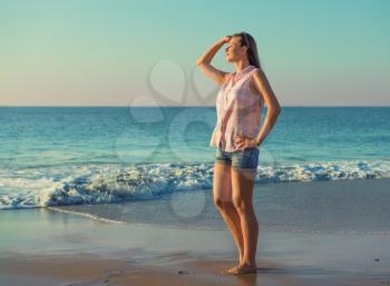 Beautiful girl on the summer beach  looking out to sea in the evening light