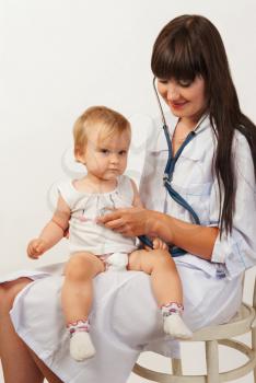 Pediatrician woman doctor with baby girl patient on light background