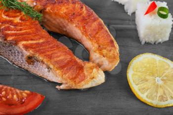 Grilled salmon with vegetables and rice on  wooden background