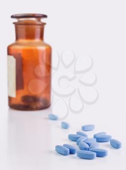 Blue pills and brown medical bottle on white background
