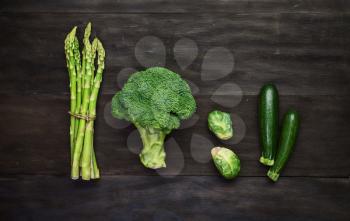 Fresh green organic vegetables on black wooden vintage table.Top view