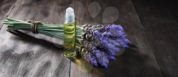 fresh lavender flowers and essential oil as natural aromatherapy for headache and migraine relief on old wooden background