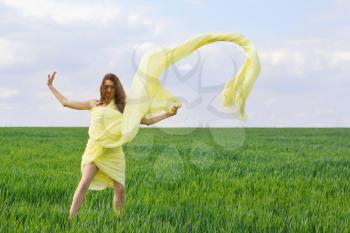 Cute young woman dancing in a green field