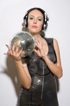 Portrait of beautiful young brunette in headphones with a mirror ball