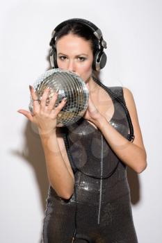 Portrait of pretty young brunette in headphones with a mirror ball