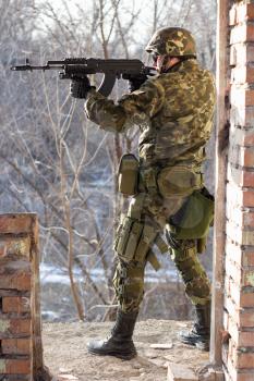 Soldier standing near wall with a gun in his hands