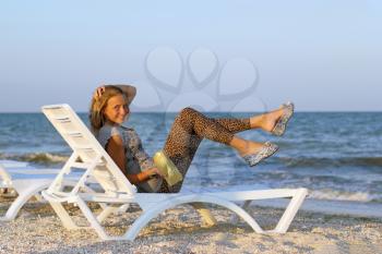 Joyful beautiful teenage girl on a lounge chair