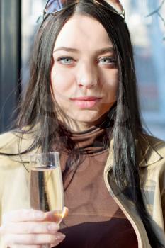 Portrait of pretty young brunette with a glass of champagne. Isolated on white