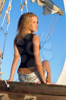 Smiling teen girl sitting at stern of the ship