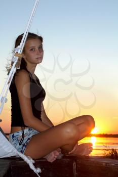 Beautiful teen girl sitting at stern of the ship