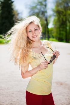 Cheerful blonde posing with sunglasses in the park