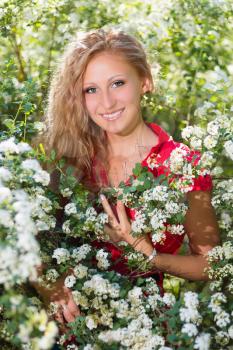 Young smiling lady posing near the flowering bush