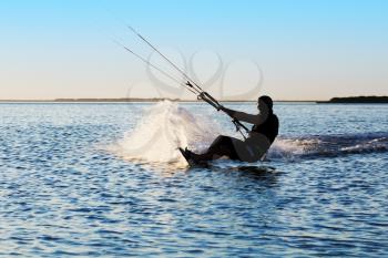 Silhouette of a kitesurfer sailing in the sea at sunset