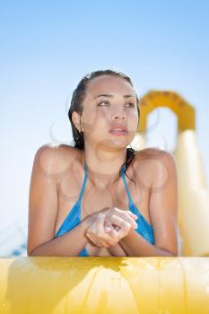 Young thoughtful caucasian woman posing on the edge of yellow pool