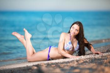 Cheerful young brunette lying on the beach
