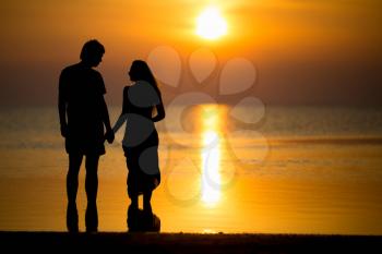 Silhouette of young couple posing on the beach at sunset