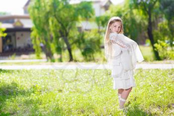 Cute little girl in white dress posing outdoors