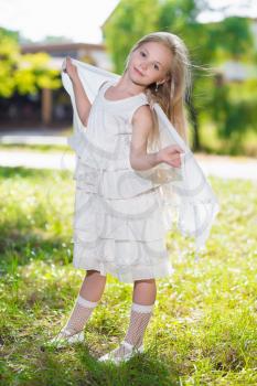 Pretty little girl in white dress posing outdoors