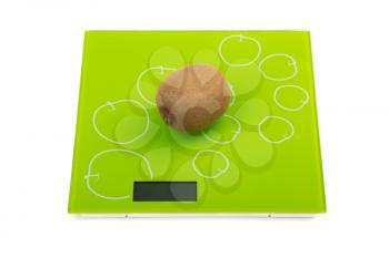 Ripe kiwi fruit on square kitchen scales. Isolated
