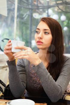 Beautiful thoughtful lady posing with a cup in the restaurant