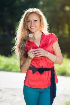 Pretty young blond woman posing with a dandelion
