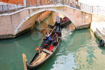 VENICE, ITALY - MAY 06, 2014: Gondolier sailing with tourists in a gondola along one of the canals in Venice, Italy