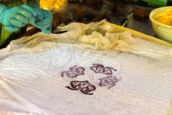Artist prints stamped pattern on fabric