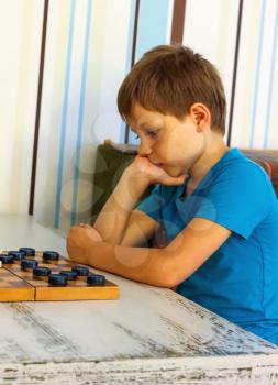 Pensive boy during a game of checkers