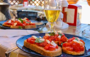Mediterranean cuisine restaurant  - sandwiches with tomatoes and  cheese on plate and glass of light beer