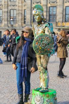 Amsterdam, the Netherlands -October 03, 2015: Young woman near the human statue street performer on Dam Square in historic city centre
