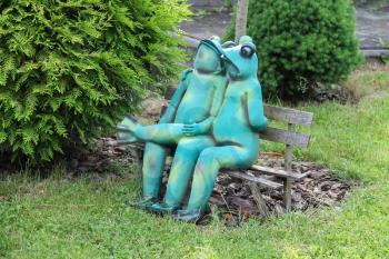 Schodnica, Ukraine - June 30, 2014: Decorative funny frogs sitting on bench in city park