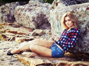 young beautiful sensual blonde girl sitting on the rocks outdoors