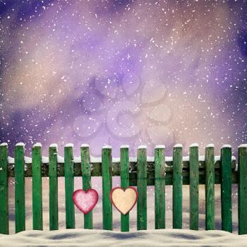 snow-covered wooden fence with two paper hearts