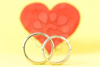 silver rings and red red  heart on yellow background