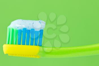 	toothbrush with toothpaste isolated on green background