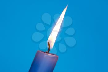 Flame of blue candle on the blue background