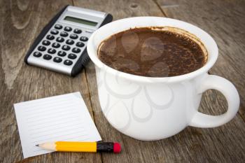 Coffee cup, calculator  and empty paper sheet with pencil on wooden background