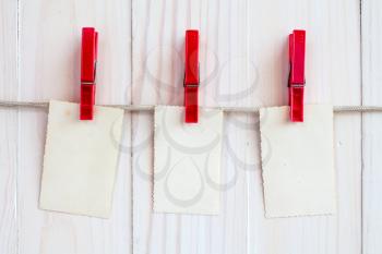 Photo frames hanging on a rope over white wooden background