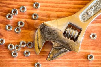 Wrench tool and nuts on the wooden background
