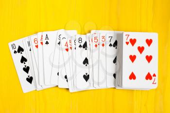 Deck of playing cards on yellow wooden background