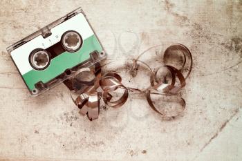 Retro audio cassette with pulled out tape on dirty canvas background
