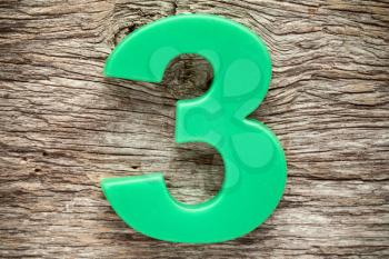 Green number three on the wooden background
