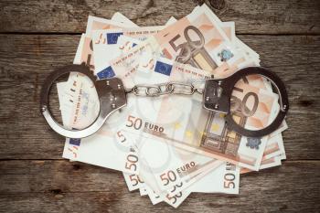Handcuffs on euro banknotes, corruption or bribery concept