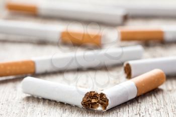 Anti-smoking background with broken cigarette on wooden surface