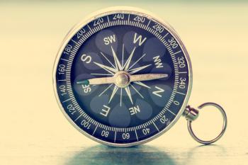 Image of old compass on wooden background. Vintage filtered and toned.