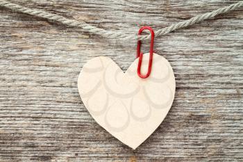 Heart made of paper hanging on wooden background